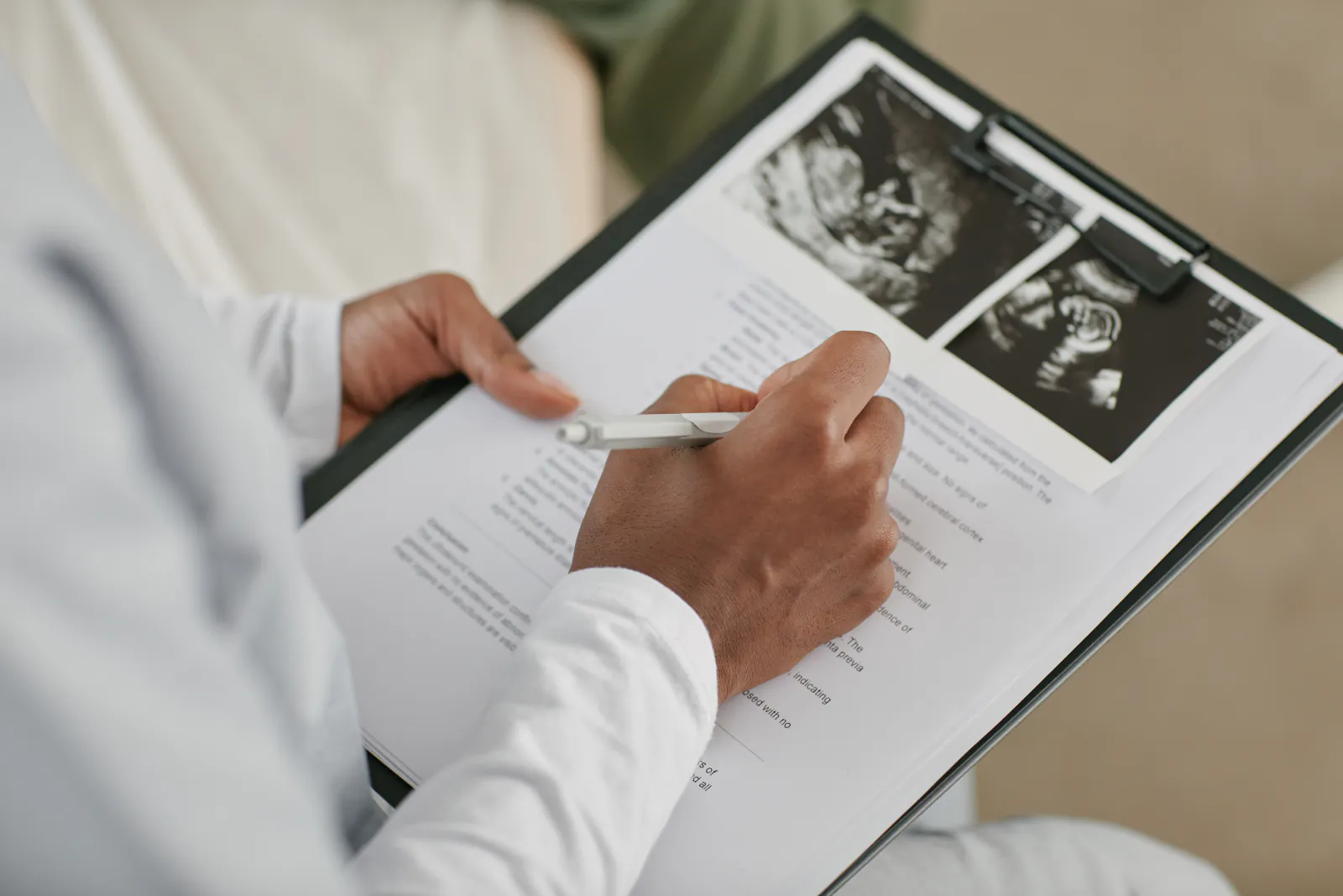 Healthcare professional writing on a medical document attached to a clipboard