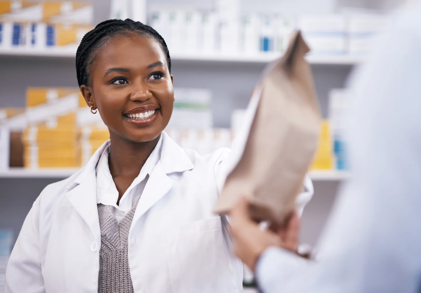 Black pharmacist providing a prepared medication package